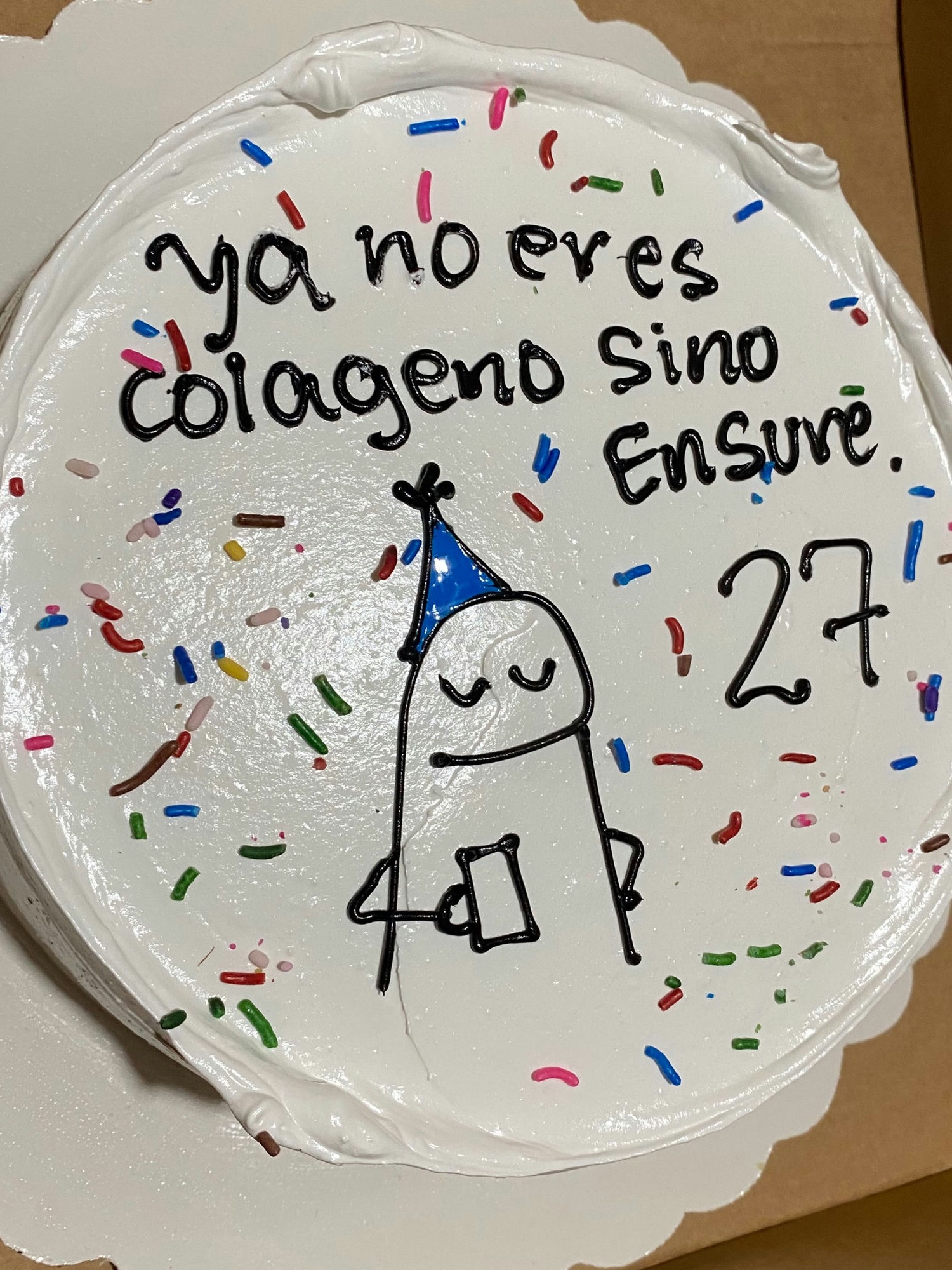 Torta de cumpleaños con confites de colores, figura dibujada y el número 27